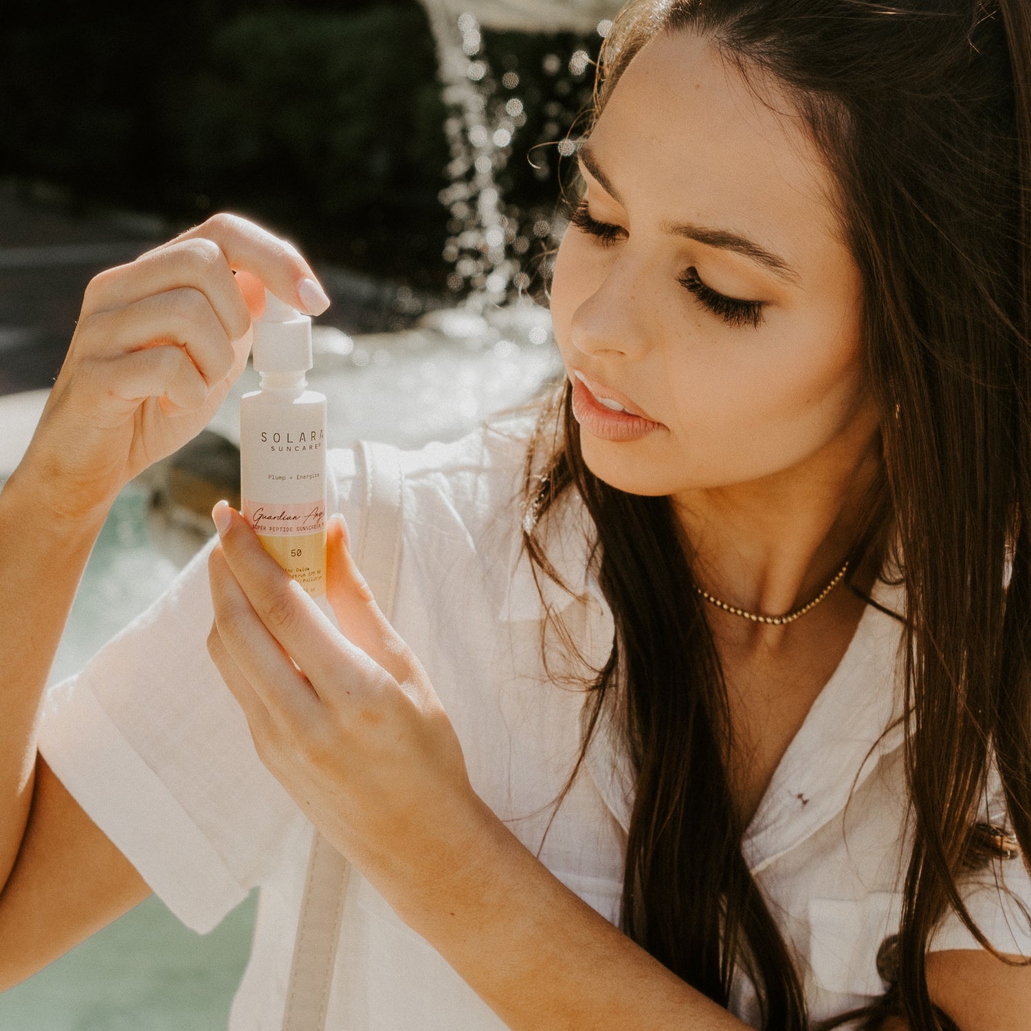 Woman applying Guardian Angel SPF 50 mineral sunscreen to face, helps address fine lines and fight free radicals, peptides plump